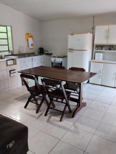 a kitchen with a wooden table and a refrigerator at Recanto Sebold in Guaratuba