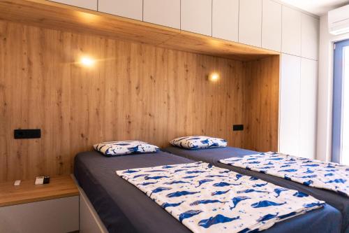 a bedroom with two beds and a wooden wall at Vila JELSANA in Jelsa