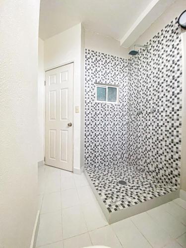 a bathroom with a shower with black and white tiles at Baja Cabo Hostal Arenal in Cabo San Lucas