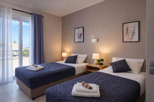 a hotel room with two beds and a balcony at Secret Garden Hotel in Maleme