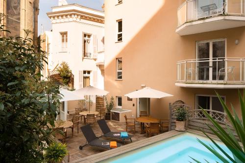 a courtyard with a pool and chairs and tables and umbrellas at Villa d'Estelle in Cannes