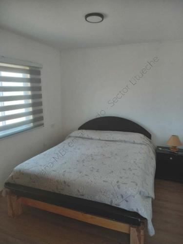 a bed in a white bedroom with a window at Cabaña en Litueche - Parcela in Cartagena