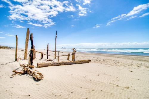 a piece of driftwood on a beach with the ocean at Sea Treasures Inn #208 in Rockaway Beach