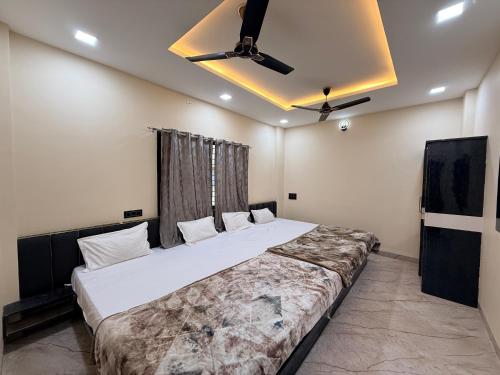 a bedroom with a large bed with a ceiling fan at Hotel Shivlok Inn in Ujjain
