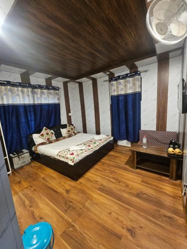 a bedroom with a bed and a table and blue curtains at The sameer resort in Anantnāg