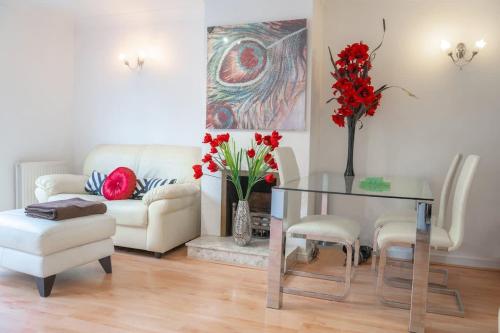 a living room with a glass table and red flowers at Stylish 3-Bed Lambeth Apartment Moments from Westminster & Brixton in London