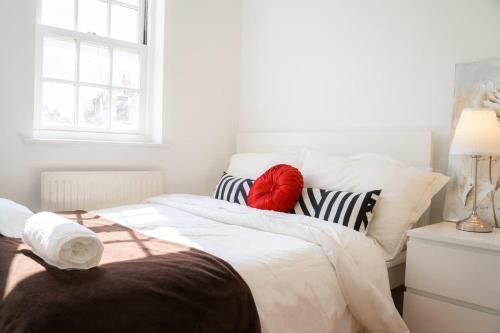 a bedroom with a bed with a red pillow on it at Stylish 3-Bed Lambeth Apartment Moments from Westminster & Brixton in London
