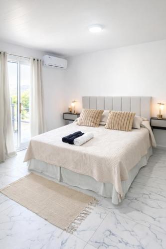 a white bedroom with a large bed with two lamps at Aura Apart in Reconquista
