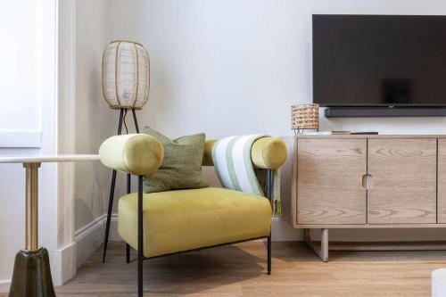 a living room with a yellow chair and a tv at The Sauchie in Glasgow