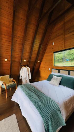 a bedroom with a large bed in a wooden room at Chalé Mont Valle in Bom Jardim da Serra