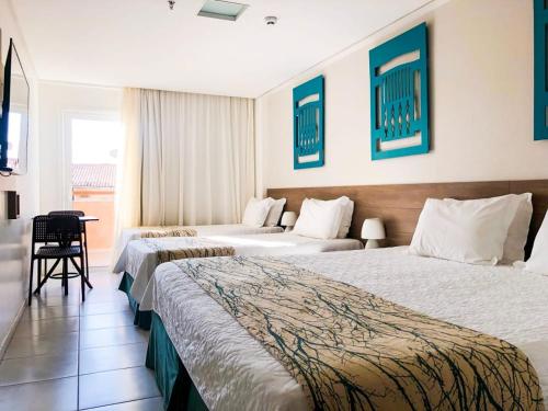 a hotel room with two beds and a table at Hotel Ponta Verde Praia do Francês in Praia do Frances