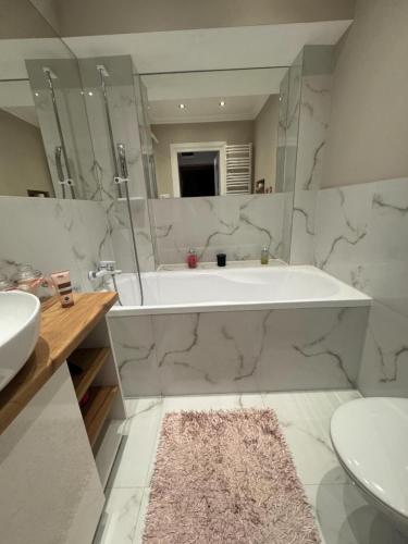 a white bathroom with a tub and a sink at !! VIP Apartament Pod BIESZCZADAMI !! in Sanok