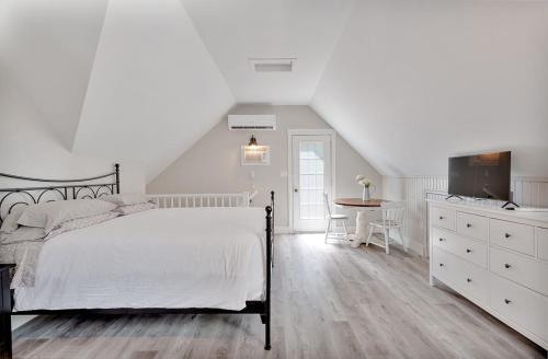 a white bedroom with a bed and a table at The Euphrates in Cavendish
