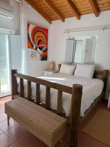 a bedroom with a large bed and a bench at Vila Brisa do Mar in Comporta