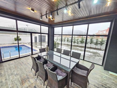 jadalnia ze stołem i krzesłami oraz basenem w obiekcie Villa Wolverine w mieście Qəbələ