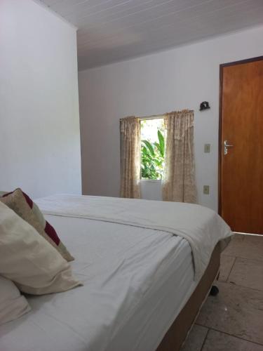 a white bed in a room with a window at Rancho da Montanha Chalé Lua in Resplendor