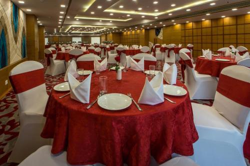 a large room with tables and chairs with red table cloth at Clarks Inn Suites Gwalior in Gwalior