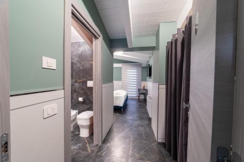 ein Badezimmer mit Toilette und ein Zimmer mit einem Bett in der Unterkunft Kora Rooms in Telese