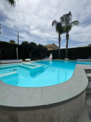 a large blue swimming pool with palm trees at Villa Panama con piscina - Mazara del vallo in Mazara del Vallo