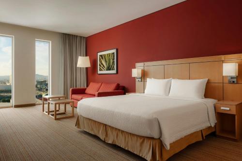 a hotel room with a bed and a red wall at Courtyard by Marriott Leon at The Poliforum in León