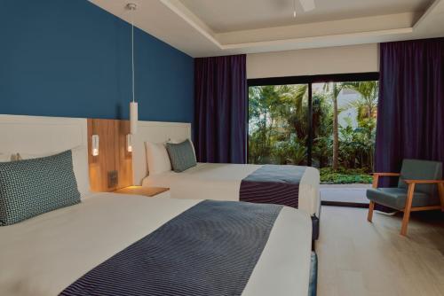 a hotel room with two beds and a window at Catalonia Yucatan Beach - All Inclusive in Puerto Aventuras