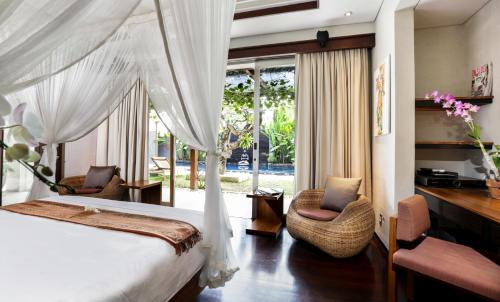a bedroom with a bed and two chairs and a window at Sunset Paradise Villa Jimbaran 8008 in Jimbaran
