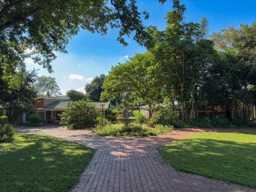 a brick walkway in a park with trees at Aintree Lodge in Pietermaritzburg