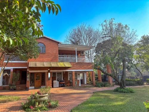 an old brick house with a porch and a yard at Aintree Lodge in Pietermaritzburg