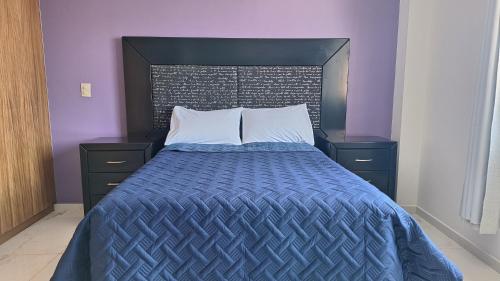 a bed with a blue comforter and white pillows at Depas Ocampo in Morelia