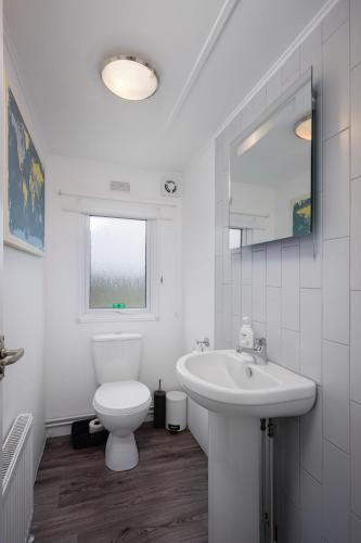 a white bathroom with a toilet and a sink at Tranquil Lodge with river views in Hambleton