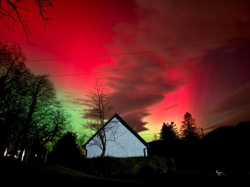 a red and green sky with a church at Highland Hideaway in Fort William