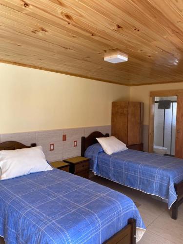two beds in a room with wooden ceilings at Residencial Golden in Los Vilos