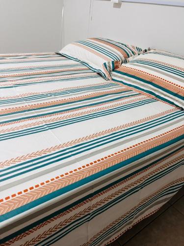 a bed with colorful sheets and pillows on it at Studio Palm Garden em Nova Andradina in Nova Andradina