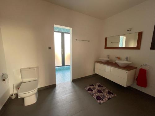 a bathroom with a toilet and a sink and a mirror at Villa Chayol - Beautiful, spacious, bright! in Cotonou