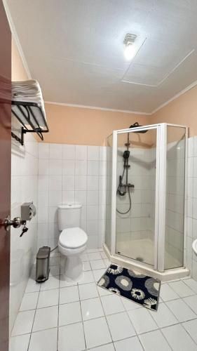 a white bathroom with a toilet and a shower at Sunset INN by Pro-Ema in Dili
