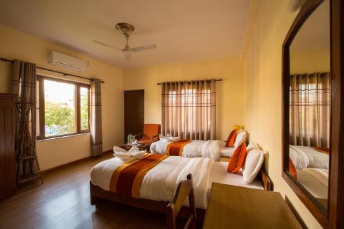 a hotel room with two beds and a mirror at Hotel Pokhara View in Pokhara