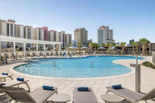 a large swimming pool with chairs and buildings at SpringHill Suites by Marriott Orange Beach Gulf Shores in Orange Beach