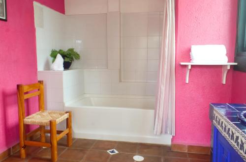 a bathroom with a white tub and pink walls at HOTEL & RESTAURANTE Los solaches in Zitácuaro