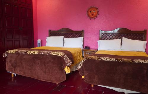 two beds in a room with pink walls at HOTEL & RESTAURANTE Los solaches in Zitácuaro