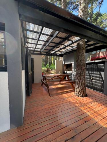 a wooden deck with a picnic table and a tree at BOSQUE LIBERTAD Casa Planta Baja in Mar Azul