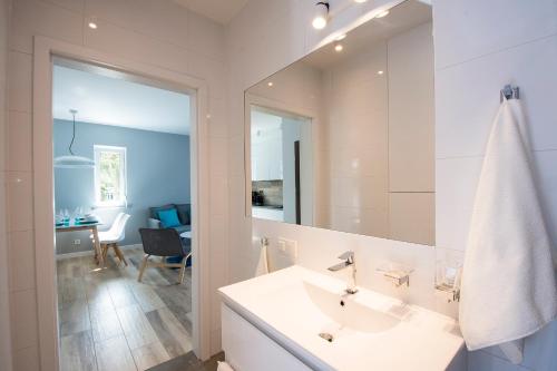 a white bathroom with a sink and a mirror at Apartament Baltic Park - BEL MARE 2 in Pogorzelica