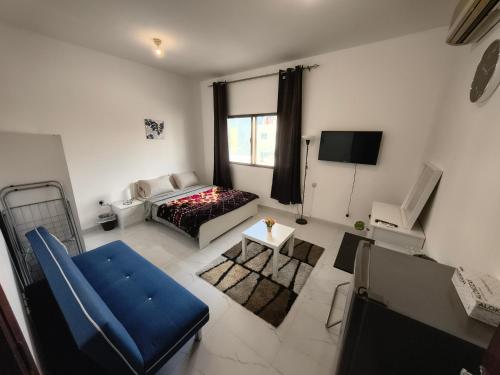 a living room with a bed and a tv at Abu Dhabi Studio in Abu Dhabi