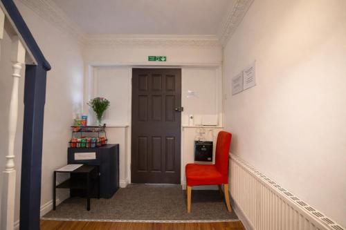 a hallway with a red chair and a door at Airport Lodge in Sheldon