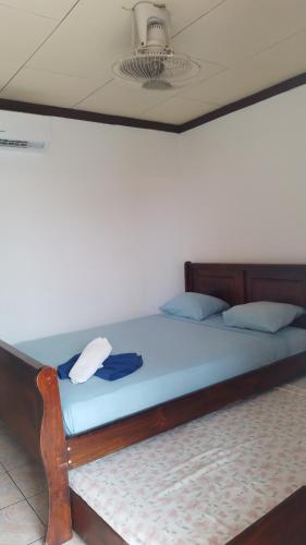 ein großes Bett mit Holzrahmen und blauer Bettwäsche in der Unterkunft Cabinas Smith 2 in Cahuita