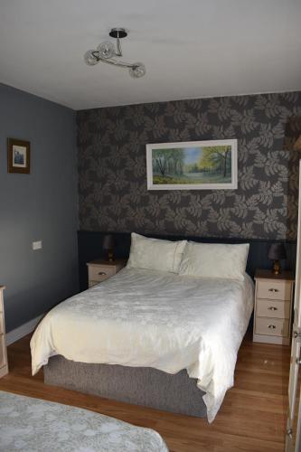 a bedroom with a white bed with a wall at Sally Gardens Cottage in Downpatrick