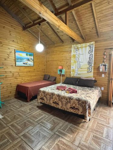 a bedroom with a bed in a wooden room at Suítes Vila Jjae in Praia do Rosa