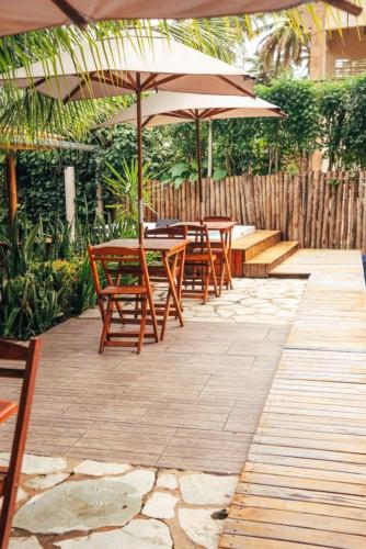 Eine Gruppe von Tischen und Stühlen mit Sonnenschirmen auf einer Terrasse in der Unterkunft Jimbaran Pousada & Bistrot in Maragogi