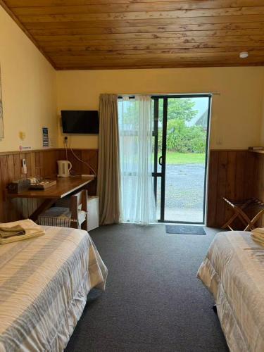 a hotel room with two beds and a sliding glass door at Mystery Creek Motel in Hamilton
