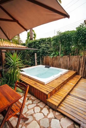 Ein Whirlpool auf einer Holzterrasse mit Sonnenschirm in der Unterkunft Jimbaran Pousada & Bistrot in Maragogi