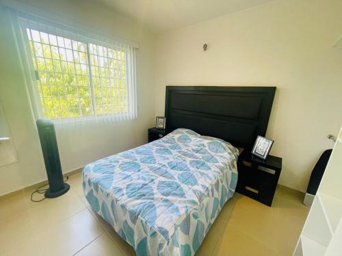 a bedroom with a bed with a blue comforter and a window at Acapulco Vibes - Departamento con Alberca Cerca de Punta Diamante in Acapulco